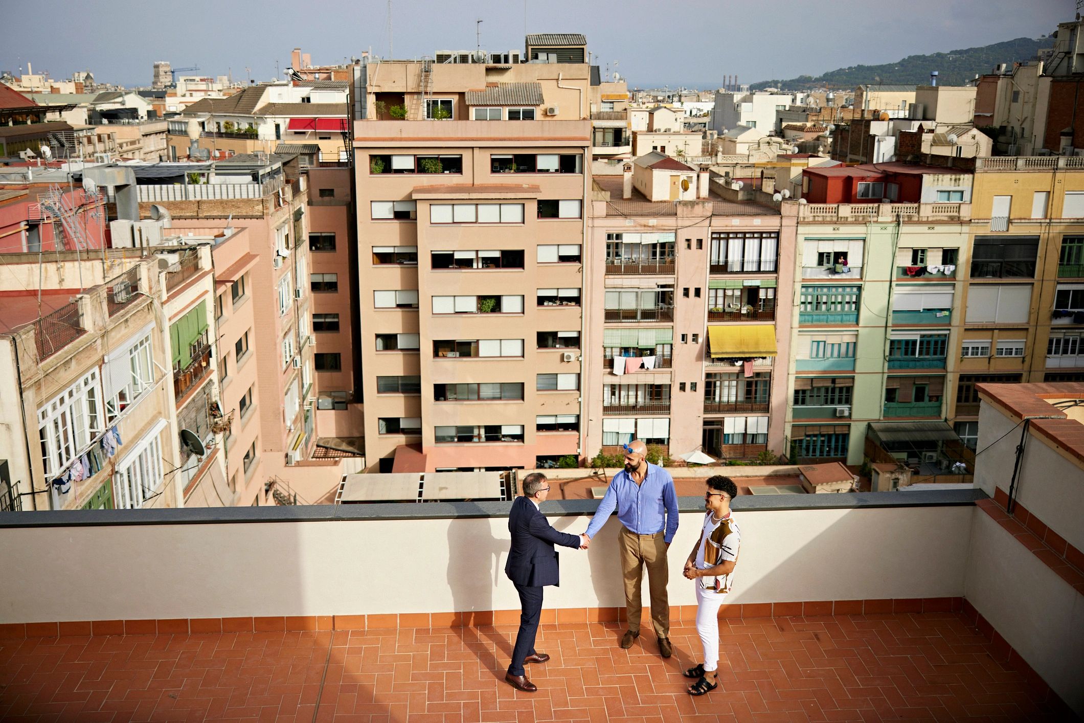 Personas en un balcón con vista a un barrio residencial, contexto de vivienda
