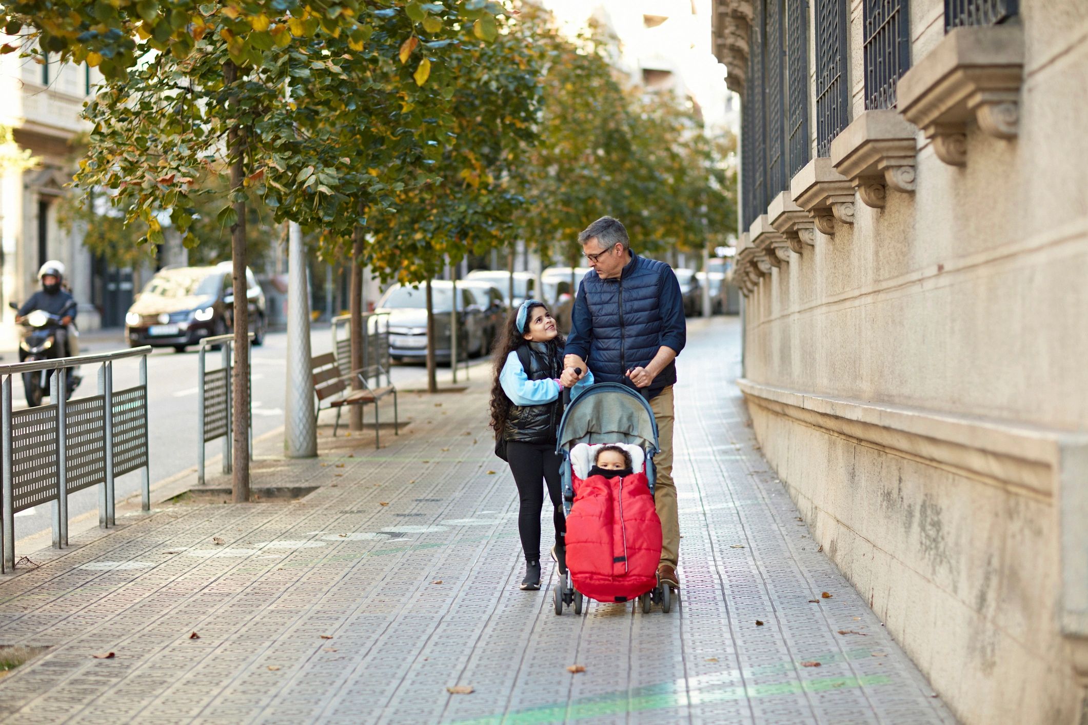 Familia caminando por una calle arbolada